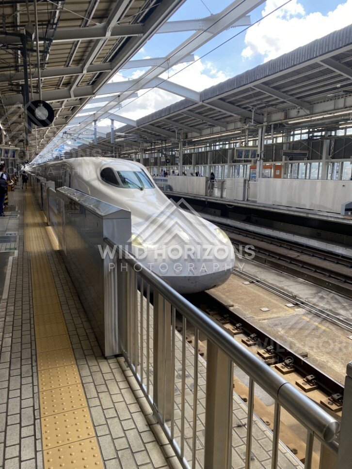 Shinkansen bullet train arriving at a platform under bright daylight. Shin-Osaka Station, Osaka, Japan.