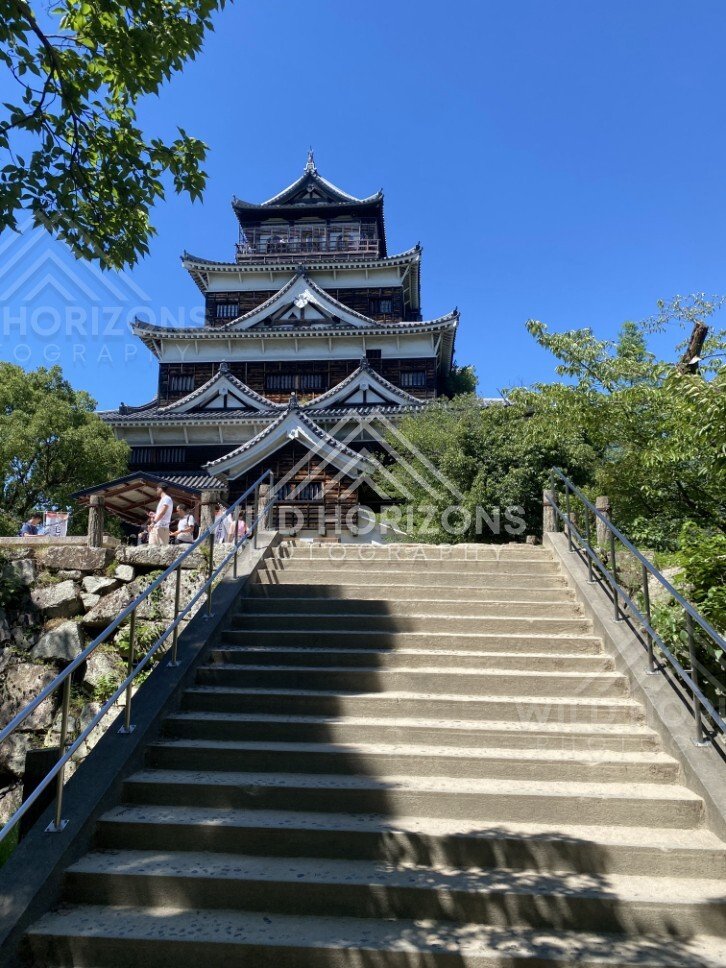 Stone steps leading up to Hiroshima Castle framed by trees. Hiroshima Castle, Hiroshima, Japan.