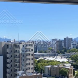 City skyline with mountains beyond and a large park complex below. Hiroshima, Japan.