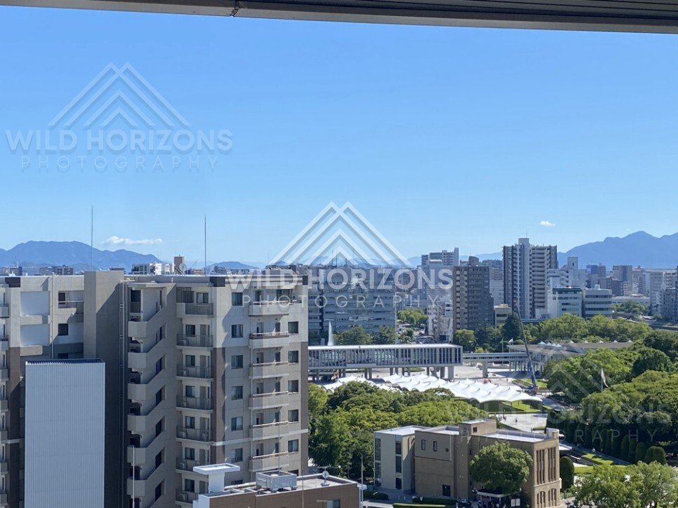 City skyline with mountains beyond and a large park complex below. Hiroshima, Japan.