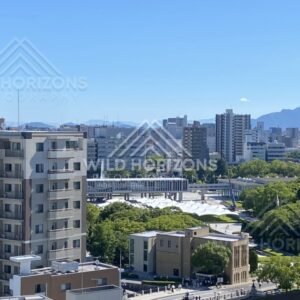 Urban skyline and green parkland viewed from above in crisp midday light. Hiroshima, Japan.