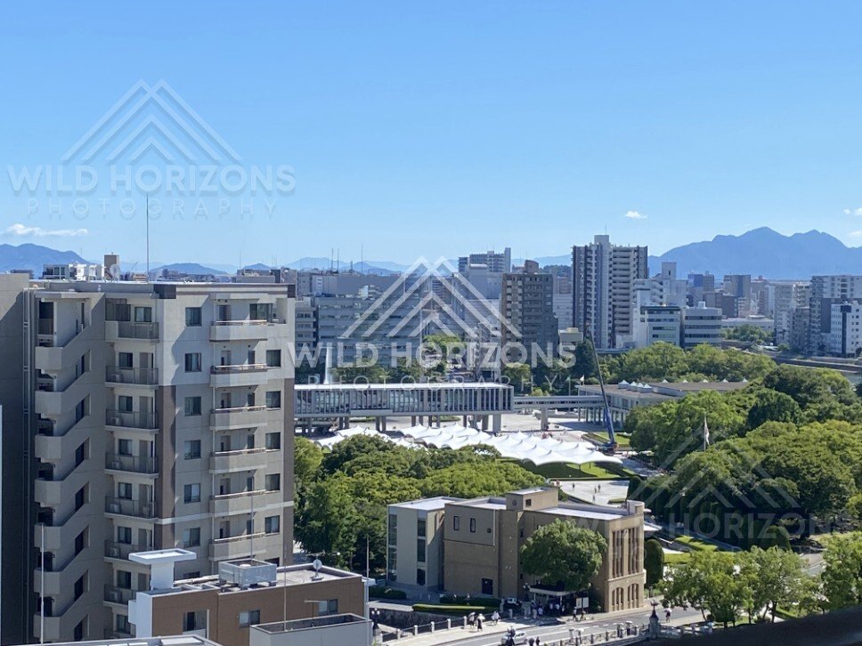 Urban skyline and green parkland viewed from above in crisp midday light. Hiroshima, Japan.