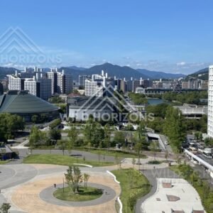 Wide city panorama with distinctive civic buildings and open plazas below. Hiroshima, Japan.