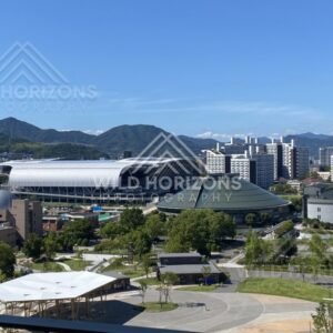 Stadium and civic buildings set against forested hills beyond the city. Hiroshima, Japan.