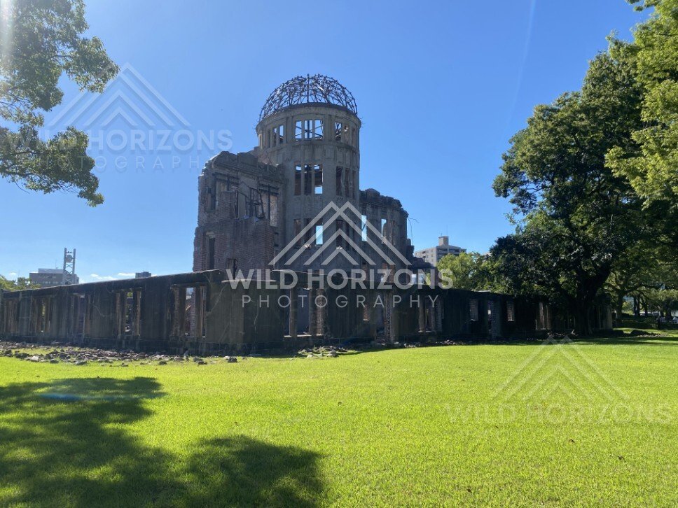 Wide view of the Atomic Bomb Dome framed by trees and open lawn. Hiroshima Peace Memorial, Hiroshima, Japan.