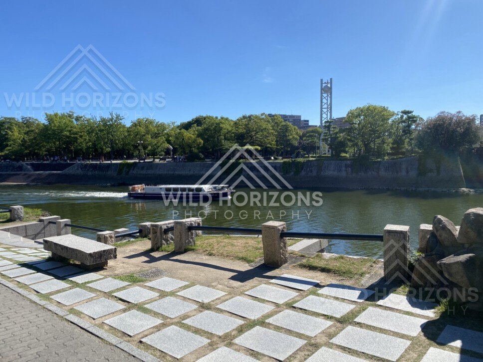 Riverside promenade with a boat passing along the waterway in Hiroshima. Hiroshima, Japan.