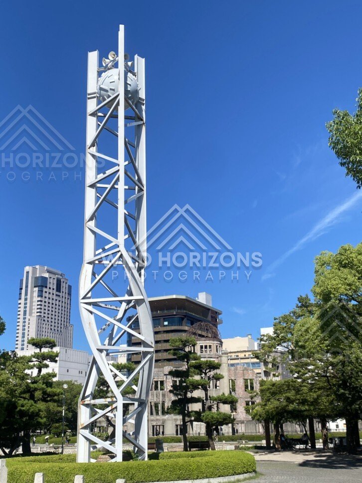 White lattice tower rising above trees and historic buildings in the park. Hiroshima Peace Memorial Park, Hiroshima, Japan.