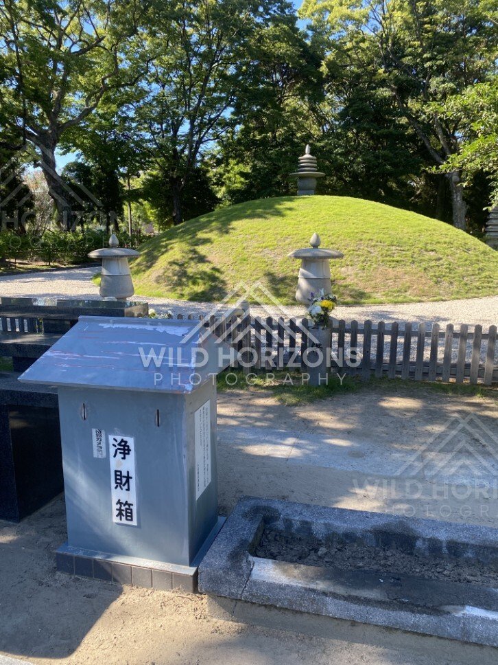 Small grassy memorial mound with a stone lantern and offering box. Hiroshima Peace Memorial Park, Hiroshima, Japan.