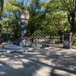 Memorial mound and monument set within tree-filled Peace Memorial Park. Hiroshima Peace Memorial Park, Hiroshima, Japan.