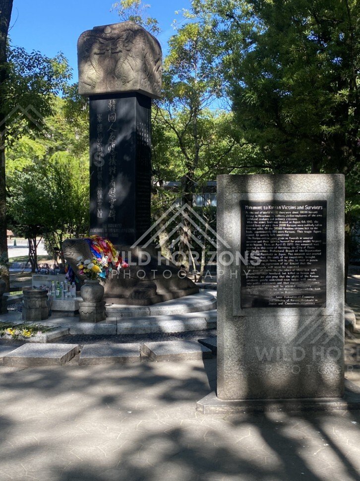 Stone memorial monument beneath trees in Hiroshima Peace Memorial Park. Hiroshima Peace Memorial Park, Hiroshima, Japan.