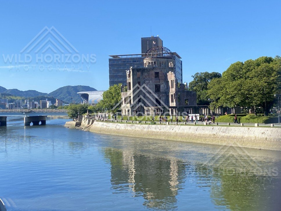 Atomic Bomb Dome reflected in calm river waters under bright sunlight. Hiroshima Peace Memorial, Hiroshima, Japan.