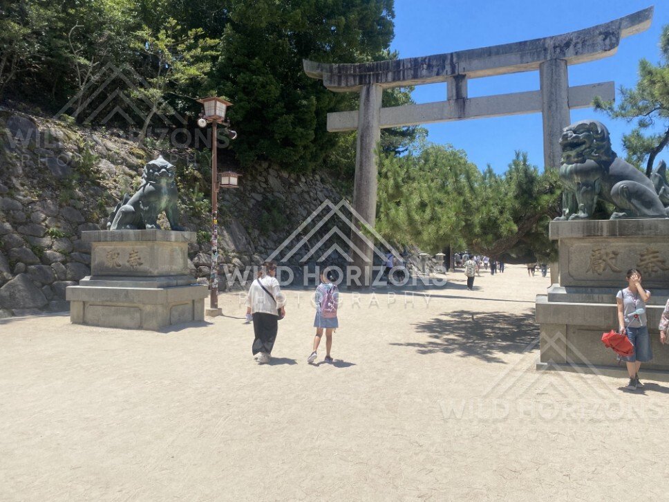 Stone torii gate and guardian statues at the entrance to Itsukushima Shrine. Miyajima, Hiroshima, Japan.