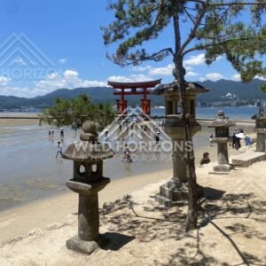 Stone lanterns framing the offshore torii gate at low tide. Miyajima, Hiroshima, Japan.