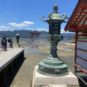 Bronze lantern overlooking the tidal flats and offshore torii gate. Miyajima, Hiroshima, Japan.