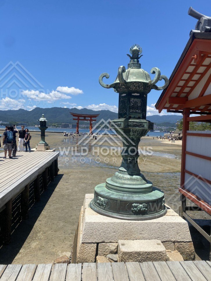 Bronze lantern overlooking the tidal flats and offshore torii gate. Miyajima, Hiroshima, Japan.