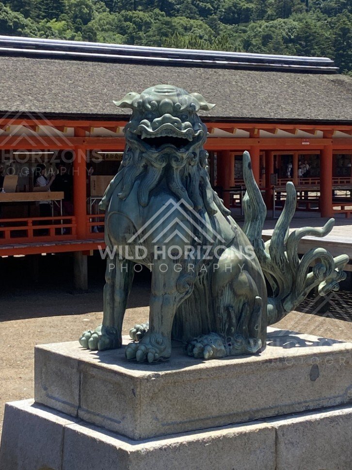 Guardian komainu statue on a stone plinth within the shrine complex. Miyajima, Hiroshima, Japan.