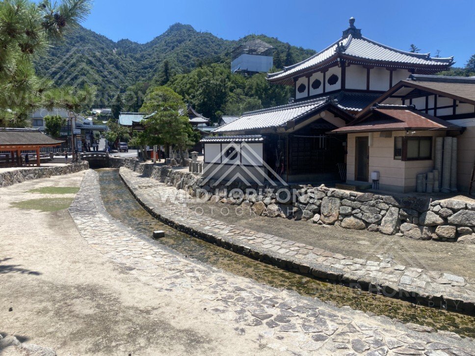 Stone-lined stream running through a traditional residential street. Miyajima, Hiroshima, Japan.