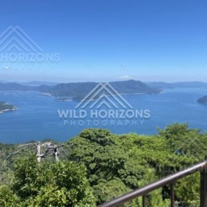 High vantage view over islands and coastline under bright blue skies. Miyajima, Hiroshima, Japan.