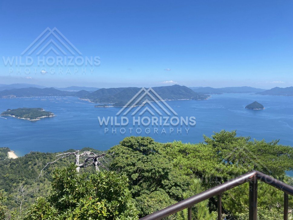 High vantage view over islands and coastline under bright blue skies. Miyajima, Hiroshima, Japan.