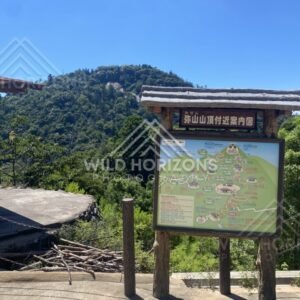 Trail map signboard at mountain lookout with hills beyond. Miyajima, Hiroshima, Japan.