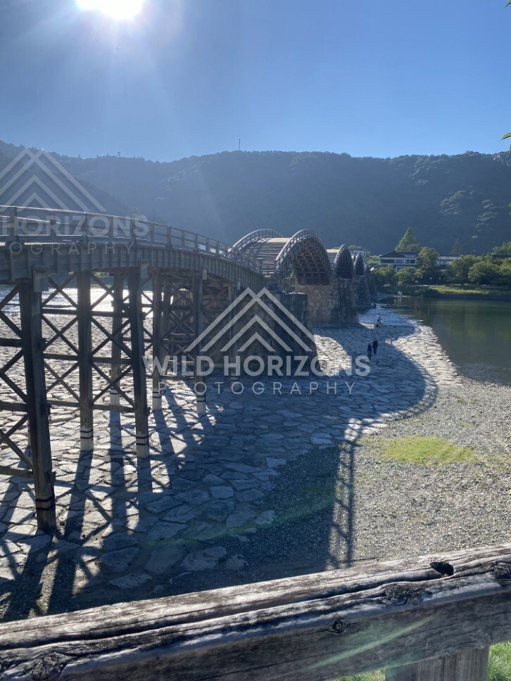 Wide view of the Kintaikyo Bridge stretching across the river at low water. Iwakuni, Yamaguchi, Japan.