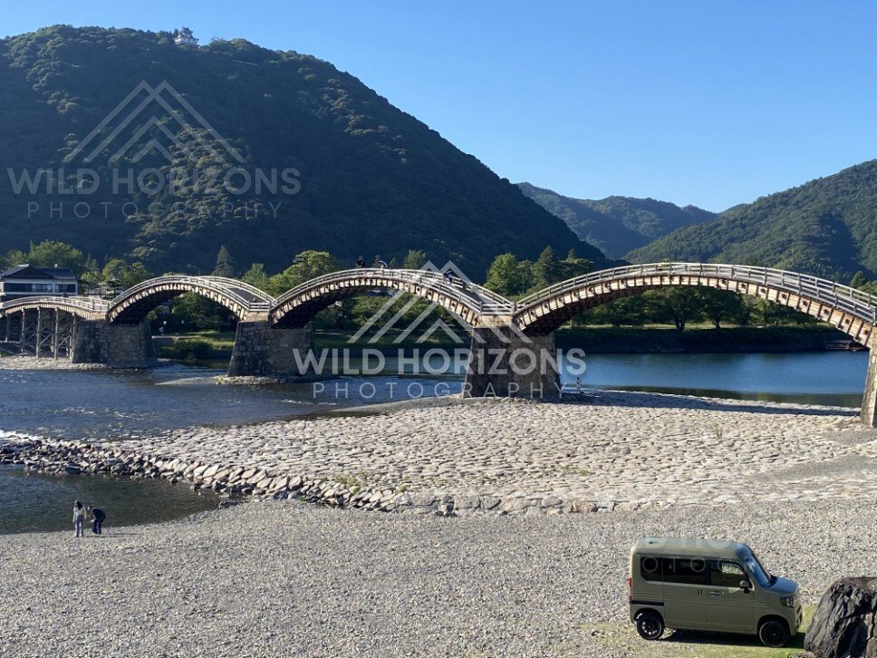 Kintaikyo Bridge framed by mountains with visitors below. Iwakuni, Yamaguchi, Japan.