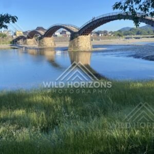 Kintaikyo Bridge crossing a shallow river under bright blue skies. Iwakuni, Yamaguchi, Japan.