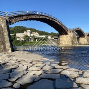 Low-angle view beneath the Kintaikyo Bridge arches over shallow water. Iwakuni, Yamaguchi, Japan.
