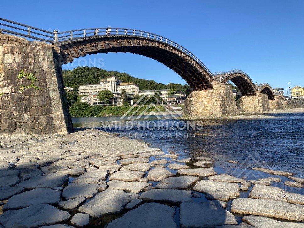 Low-angle view beneath the Kintaikyo Bridge arches over shallow water. Iwakuni, Yamaguchi, Japan.