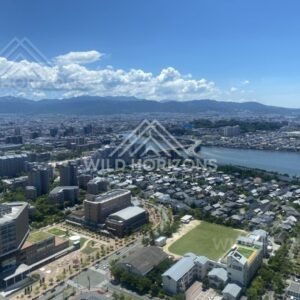 Aerial view over city and winding river under bright clouds. Fukuoka, Japan.