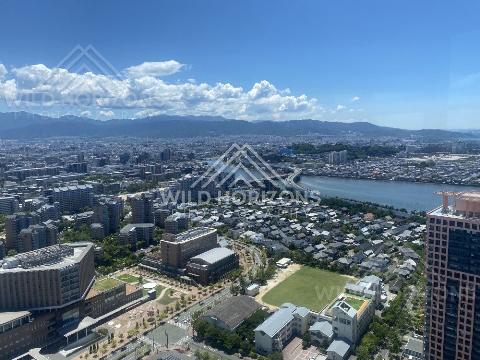 Aerial view over city and winding river under bright clouds. Fukuoka, Japan.