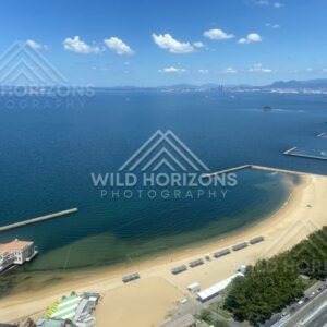 Wide coastal panorama with beach, sea, and distant city skyline. Fukuoka, Japan.
