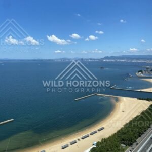 Elevated coastal view with beach, road, and offshore structures. Fukuoka, Japan.