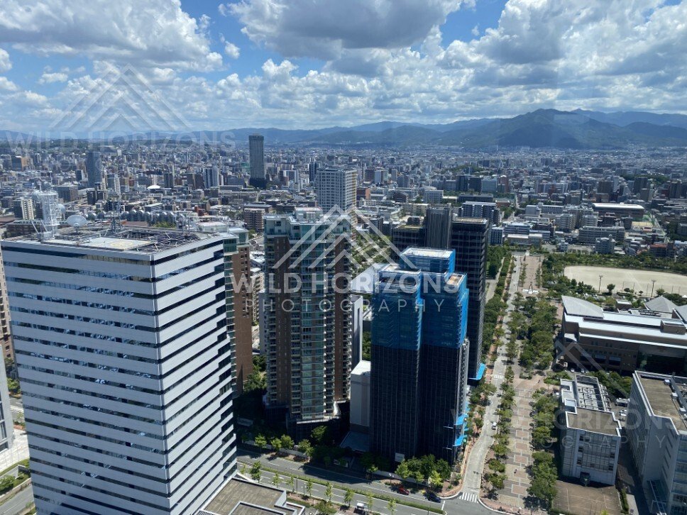 City skyline viewed from high elevation beneath textured clouds. Fukuoka, Japan.