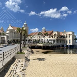 Beachfront building on stilts beside calm bay and sandy shore. Fukuoka, Japan.