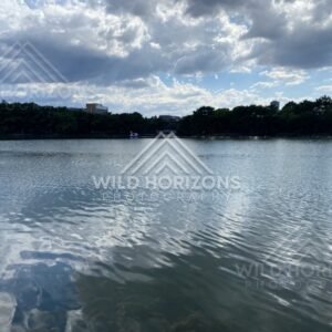 Cloud reflections ripple across a city lake under a wide summer sky. Fukuoka, Japan.