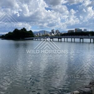 A long pedestrian bridge crosses the lake toward the city skyline. Fukuoka, Japan.
