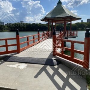 A red pavilion and walkway extend out over the lake under towering clouds. Fukuoka, Japan.