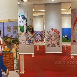 Hanging banners display colourful Hello Kitty themed artwork inside an exhibition space. Fukuoka, Japan.