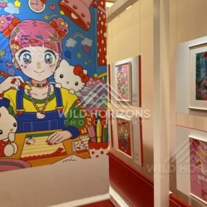 A large Hello Kitty mural stands beside framed artworks in a brightly lit gallery. Fukuoka, Japan.
