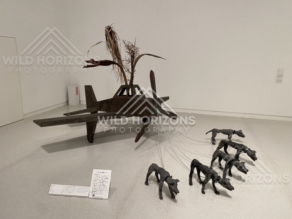 Contemporary sculpture installation featuring a plane-like form and chained dog figures. Fukuoka, Japan.