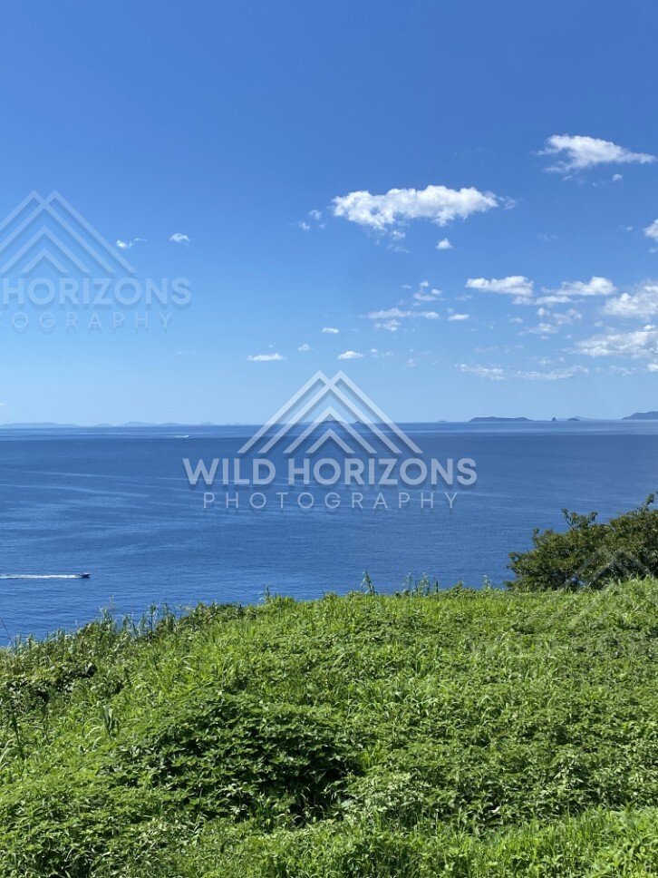 Ocean horizon and distant islands seen from a grassy headland. Nagasaki, Japan.
