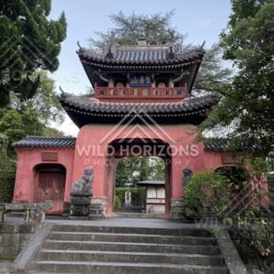 Traditional temple gate with tiled roof and guardian statues. Nagasaki, Japan.