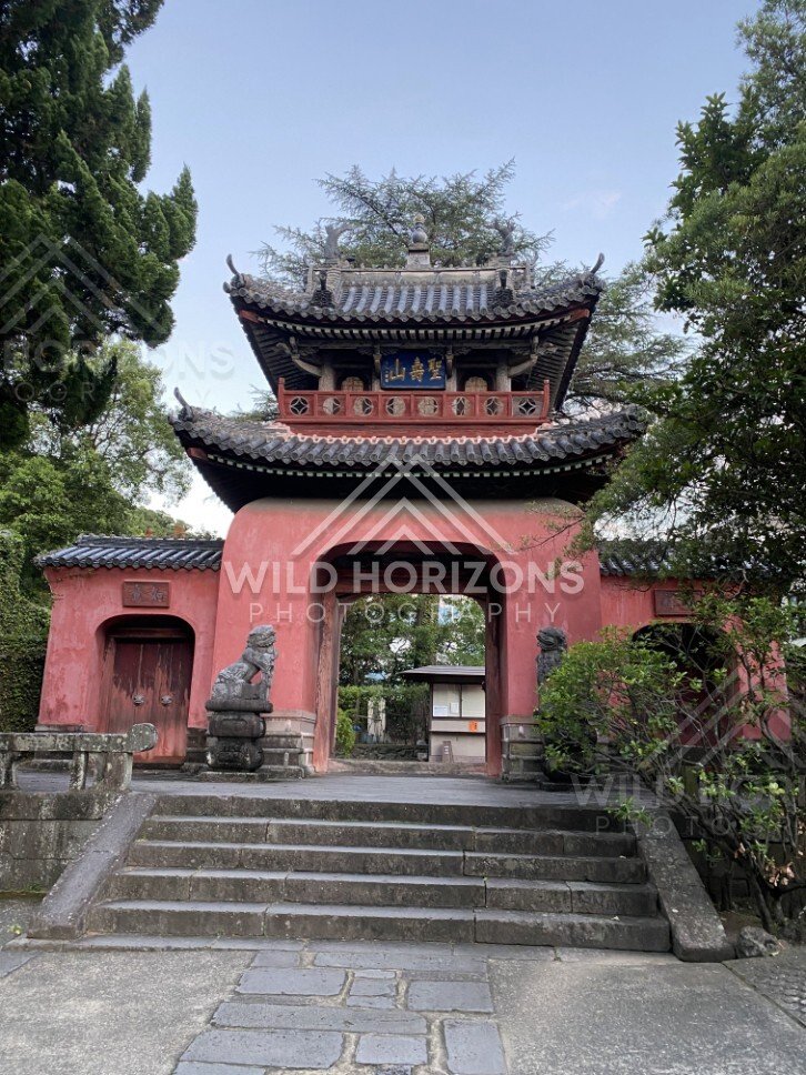 Traditional temple gate with tiled roof and guardian statues. Nagasaki, Japan.