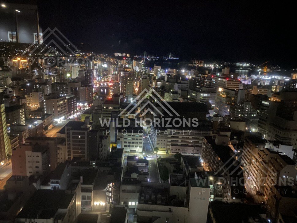 Night city skyline with harbour lights viewed from a high observation point. Nagasaki, Japan.