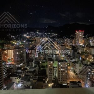 Night cityscape with glowing streets and mountains silhouetted beyond the skyline. Nagasaki, Japan.