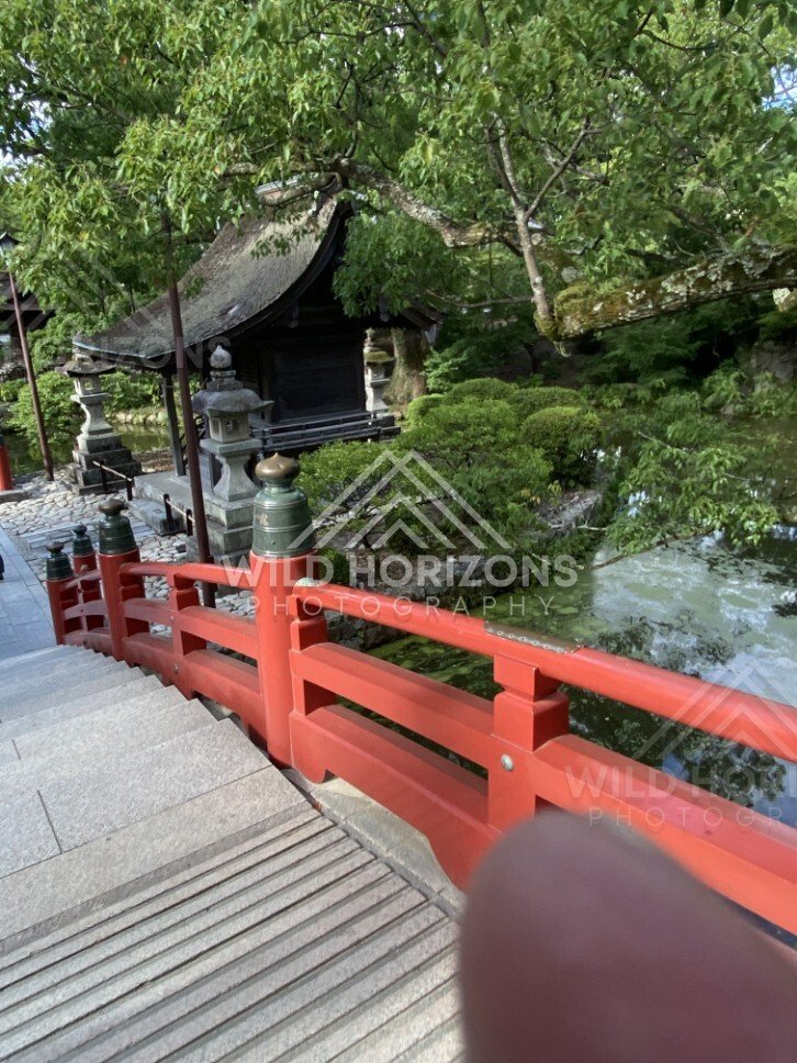 Red Bridge Railings Beside a Small Shrine Pavilion and Waterway. Fukuoka, Japan.