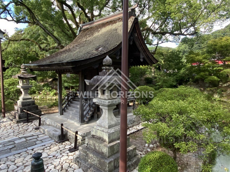 Stone Lanterns and Thatched Roof Shrine Pavilion in a Garden Setting. Fukuoka, Japan.