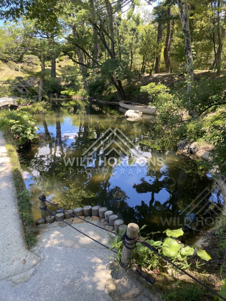 Wooded Pond Edge with a Small Boat in Shukkeien Garden. Hiroshima, Japan.