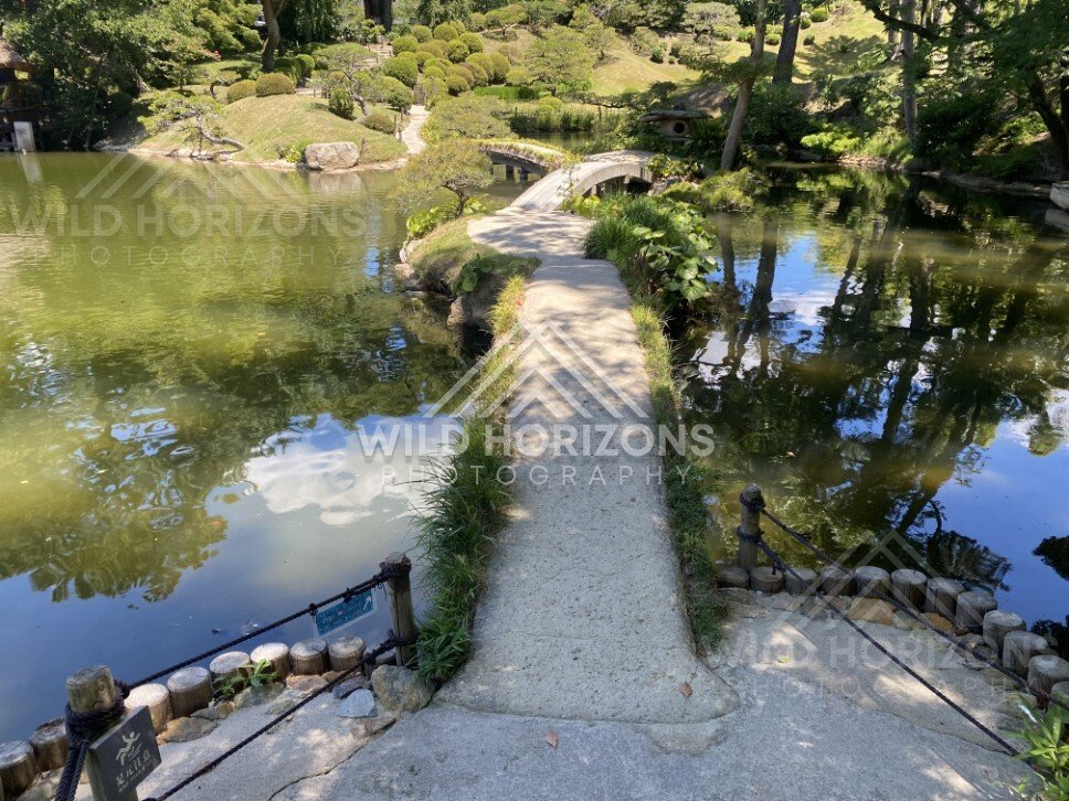 Stone Path and Arched Bridge Crossing the Garden Pond. Hiroshima, Japan.